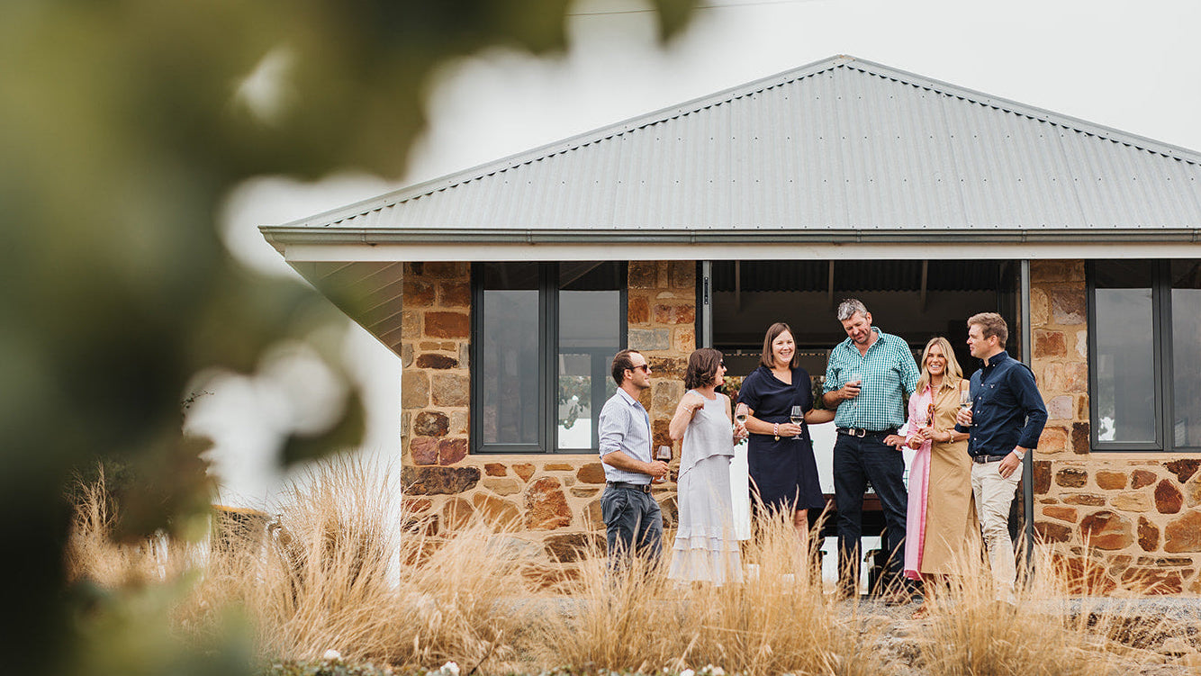 Group of people standing outside a stone house with a blurred background